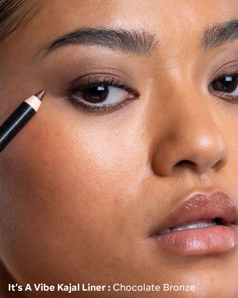 Close-up of a person applying Kajal eyeliner with a pencil, featuring 'It's A Vibe Kajal Liner' product.