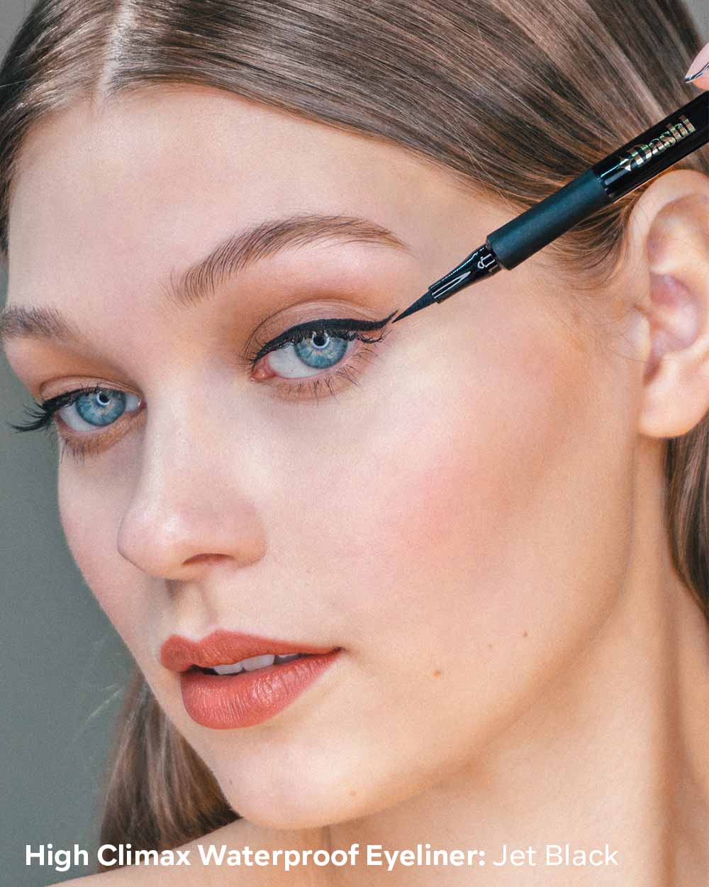 Woman applying eyeliner with a focus on the eyeliner product.